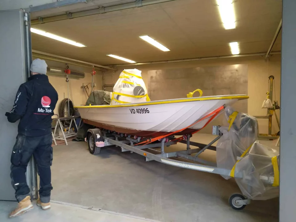 Boot auf seinem Anhänger bei der Einfahrt in die Strahlkabine der Werkstatt in Develier