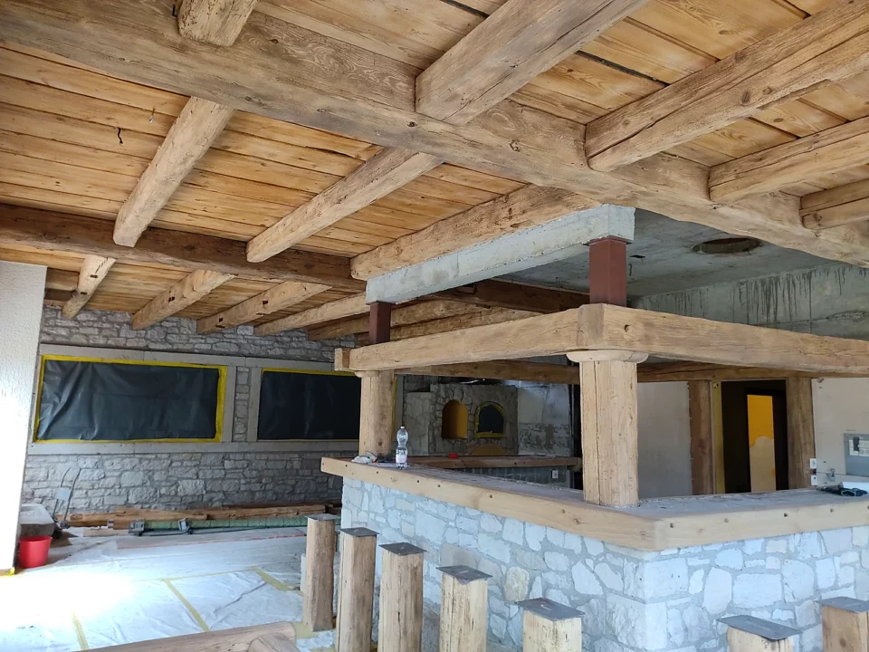 Plafond à poutres apparentes et bar en bois sablés, murs et sol protégés par des bâches