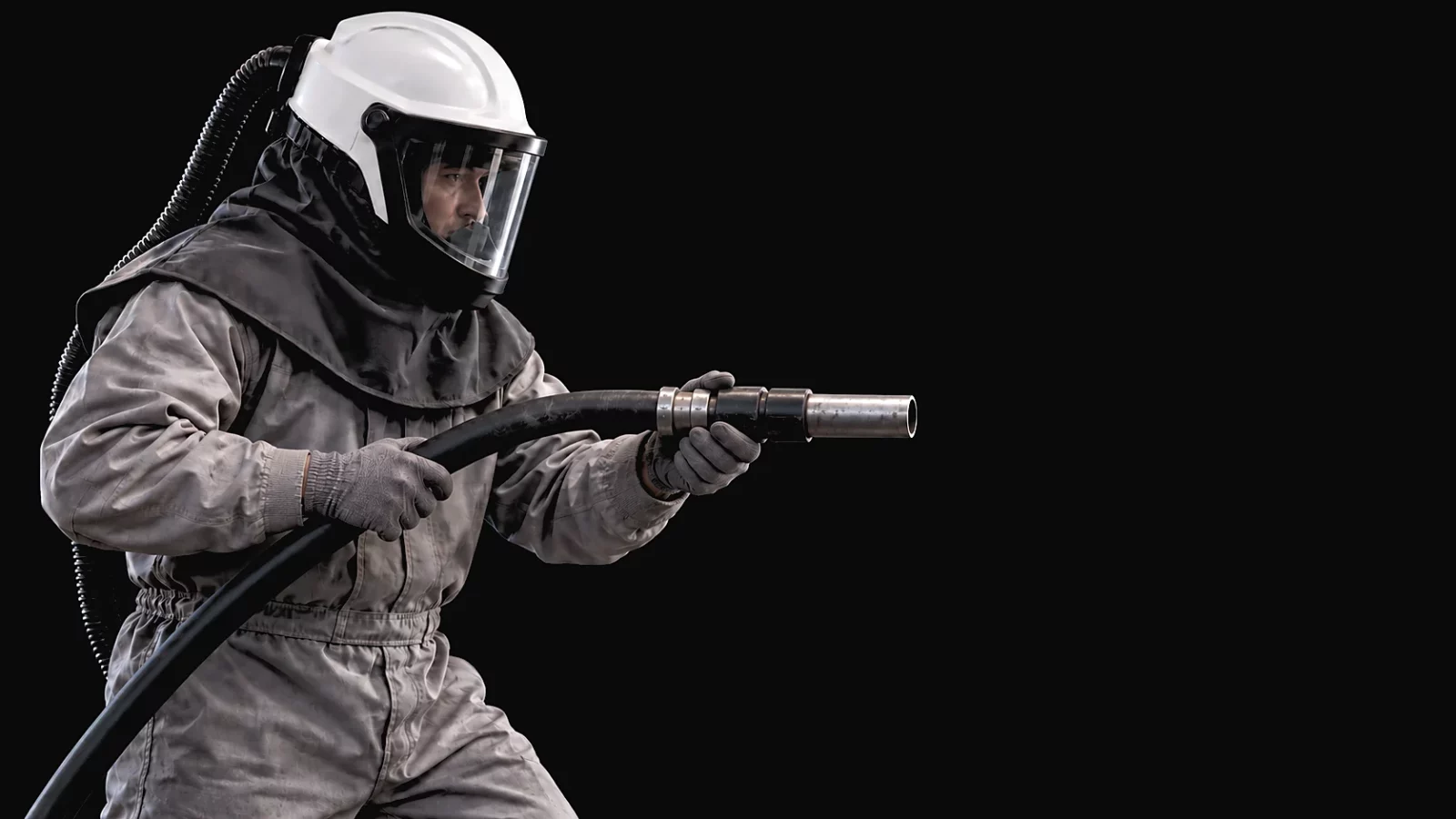 Strahler in Schutzanzug mit belüftetem Helm, Strahldüse in der Hand